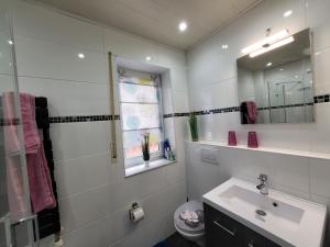 ein weißes Badezimmer mit einem Waschbecken und einem Spiegel in der Unterkunft Ferienwohnung Schardt in Annweiler am Trifels