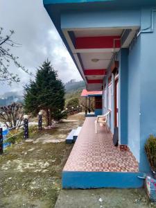 a blue building with a bench on a walkway at The Himalayan Resort in Ravangla