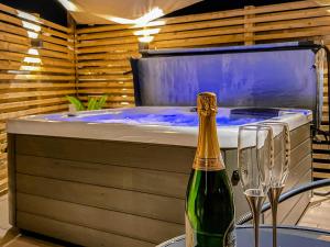 uma garrafa de champanhe sentada ao lado de uma banheira de hidromassagem em Dovecote em Stoke Bruerne