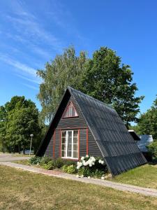 ein kleines rotes Haus mit schwarzem Dach in der Unterkunft Radi in Brocēni