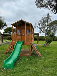 een houten speeltuin met een glijbaan en een speelhuis bij Serenity by the Sea Cottage in Apollo Bay with Jacuzzi in Marengo