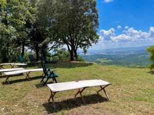 two picnic tables and chairs on top of a hill at Agriturismo Cetamura in Castelnuovo Berardenga