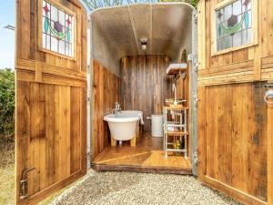 a bathroom with a tub in a wooden building at Dennis in Llanwnda