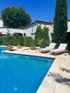 una piscina con 2 tumbonas junto a una casa en Le Mas Angelussi - Le Clos du Soleil en Salon-de-Provence