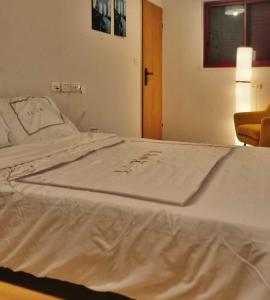 a bed in a room with a white blanket on it at המקום של ענת. Anat's place in Tel ‘Adashim