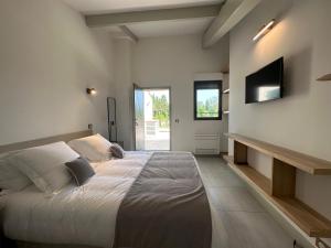 a bedroom with a large bed and a flat screen tv at Mas Sourso in Eygalières