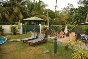 un cortile con sedie, ombrellone e piscina di Villa Nemo a Wayikkal