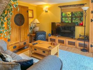 uma sala de estar com uma televisão e uma mesa em Yelt Cottage em Wootton