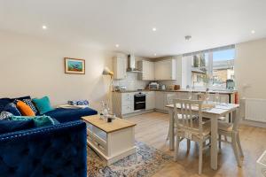 a living room with a blue couch and a kitchen at 1 Chapel Mews in Sidmouth