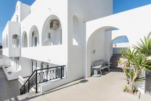 a building with white walls and a balcony with a bench at Villa Valvis in Perissa