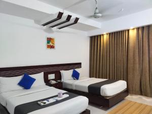 a hotel room with two beds with blue pillows at Shahjadi Resort in Cox's Bazar