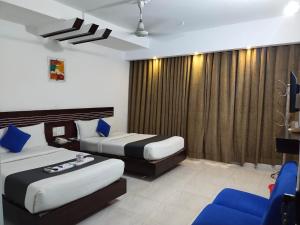 una habitación de hotel con 2 camas y una silla azul en Shahjadi Resort en Cox's Bazar