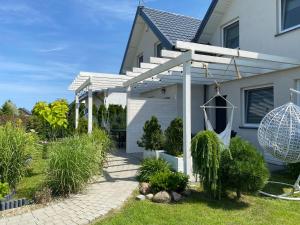 una casa con una pérgola blanca en el patio en Domki Akacjowe Zacisze, en Puck