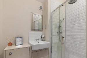 uma casa de banho branca com um lavatório e um chuveiro em 1 Chapel Mews em Sidmouth