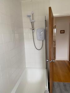 a bath tub with a shower in a bathroom at The Sheiling holiday home with gorgeous views over the isles in Arisaig