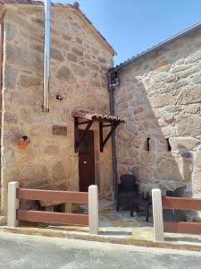 Vilar的住宿－A CASIÑA DA PALMERA，前面有两长椅的石头建筑