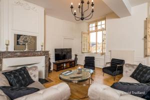 a living room with a couch and a table at Suites Mana - MATAHINA avec VUE SUPERBE sur la Place DUCALE et Parking privé inclus in Charleville-Mézières