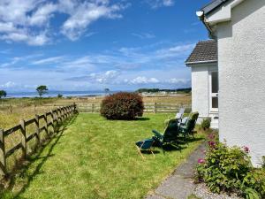 a yard with chairs and a fence and the ocean at The Sheiling holiday home with gorgeous views over the isles in Arisaig