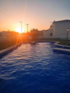 a pool with the sunset in the background at Apartamento nuevo en urbanización a 250 metros de la playa in Denia