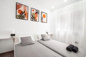 a white bedroom with a bed with two black shoes on it at Design apartment plaça La font in Tarragona