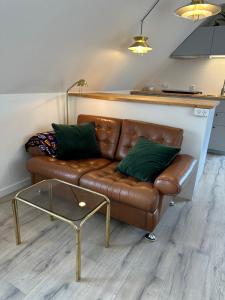 brązowa skórzana kanapa z zielonymi poduszkami w salonie w obiekcie Loftlejlighed i centrum w mieście Ringkøbing