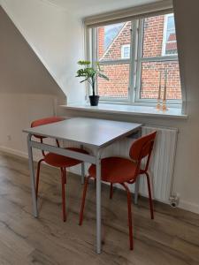 een tafel en 2 stoelen in een kamer met een raam bij Loftlejlighed i centrum in Ringkøbing