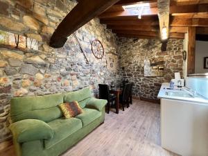 sala de estar con sofá verde y pared de piedra en Mirador de Lanchares, en Lanchares