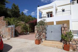 una casa blanca con una puerta y algunas plantas en The Sea Star - Korfos Sea View Villa, en Korfos