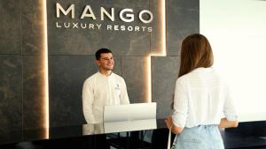 a man and a woman standing in front of a company sign at Mango Luxury Resorts in Sarandë