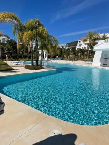 basen z błękitną wodą i palmami w obiekcie Alcazaba Blue Lagoon 3 bedroom, Ground floor Apartment w mieście Estepona