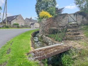 uma velha parede de pedra com escadas ao lado de uma estrada em Yelt Cottage em Wootton