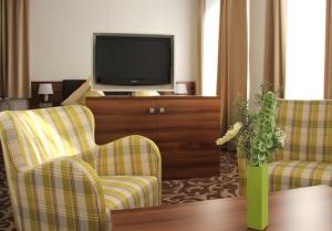 a living room with two chairs and a television at Hotel Winter in Schöppingen