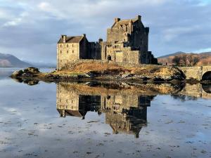 a castle on an island in a body of water at An Dòbhran - luxury self-catering in Dornie