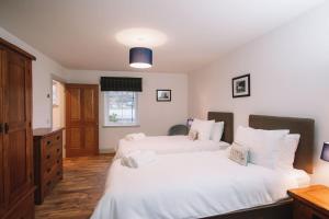 two beds in a bedroom with white sheets at An Dòbhran - luxury self-catering in Dornie