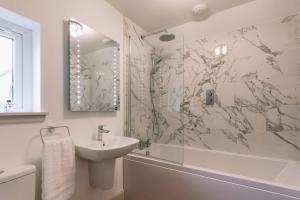 a white bathroom with a sink and a shower at An Dòbhran - luxury self-catering in Dornie