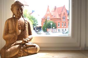 une statue assise sur le sol devant une fenêtre dans l'établissement Akram Appartement II - Studio - Zentral und Ruhig, à Hildesheim