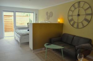 - un salon avec un canapé et un réveil sur le mur dans l'établissement Akram Appartement II - Studio - Zentral und Ruhig, à Hildesheim