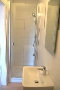 La salle de bains blanche est pourvue d'une douche et d'un lavabo. dans l'établissement Akram Appartement II - Studio - Zentral und Ruhig, à Hildesheim