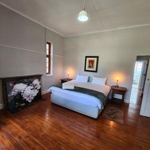 a bedroom with a white bed and a fireplace at Karoo Leeu Self Catering in Oudtshoorn