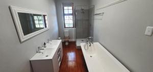 a white bathroom with two sinks and a bath tub at Karoo Leeu Self Catering in Oudtshoorn +56 photos