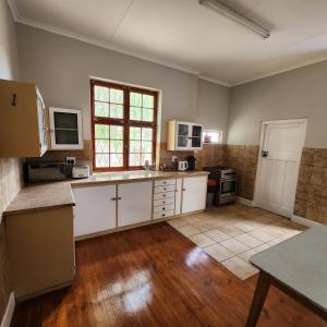 a large kitchen with white cabinets and a wooden floor at Karoo Leeu Self Catering in Oudtshoorn