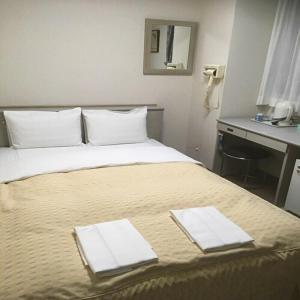 a hotel room with a bed with two towels on it at Hotel Tetora Kasugai Station Hotel in Kasugai