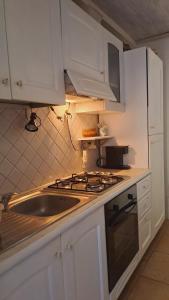 een keuken met een wastafel, een fornuis en witte kasten bij La Casa di Cesi in San Gemini