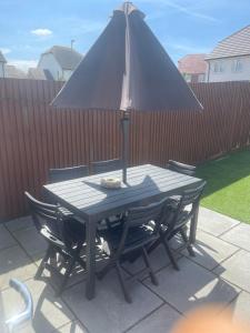 a table and chairs with an umbrella on a patio at Graceful Home Away Sittingbourne 3BH in Kent