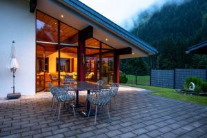 a house with a table and chairs on a patio at Hubertus Gartenlodge in Mittelberg