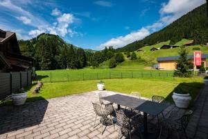 a patio with a table and chairs and a field at Hubertus Gartenlodge in Mittelberg