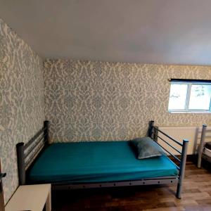 a bedroom with a bed with green sheets and a window at Hostel Monument in Bucharest