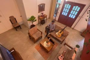 a man sitting in a living room with a guitar at El Segoviano Alojamiento Rural in Pedro Vicente Maldonado