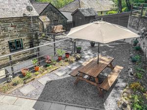 a patio with an umbrella and a wooden bench at Old Stables Cottage in Blaenporth