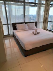 a bedroom with a bed with white sheets and windows at Holiday at Times Square KL in Kuala Lumpur